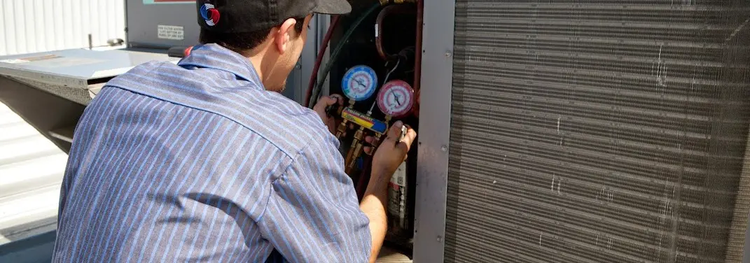 HVAC technician servicing a condenser unit in Kaukauna